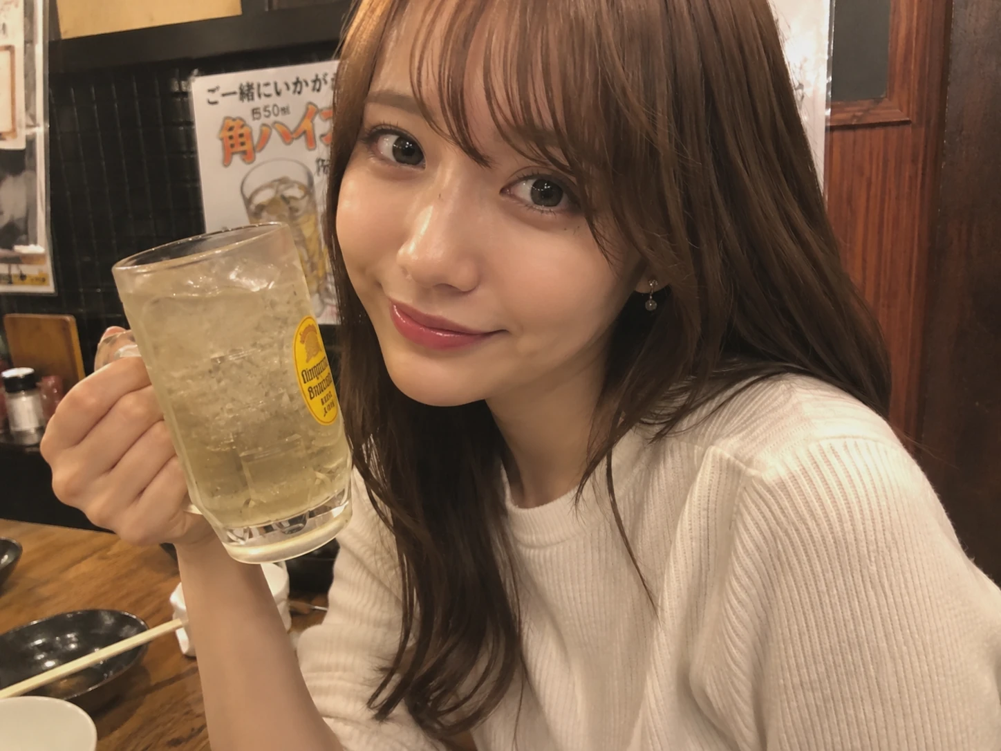 ①⑤⑧の自然さを出す指示を加えて生成した、居酒屋で友人に撮影された架空の成人日本人女性のAI画像