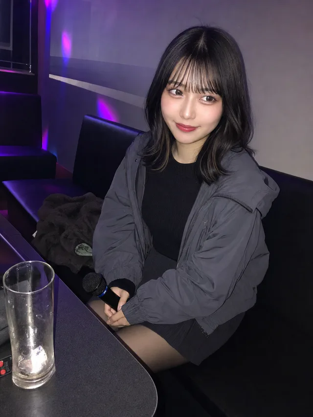 深夜のカラオケ個室で、歌い終えた成人女性が友達へ可愛く微笑むAI生成のスマホ写真