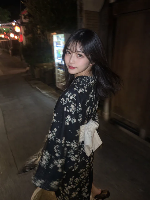 夜の細い路地で、黒地に小花柄の浴衣と白い帯を着た黒髪の成人女性が振り返るAI生成のスマホ写真