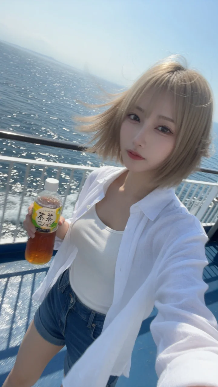 フェリー甲板でお茶を持ち風に髪がなびく砂色ボブの日本人女性