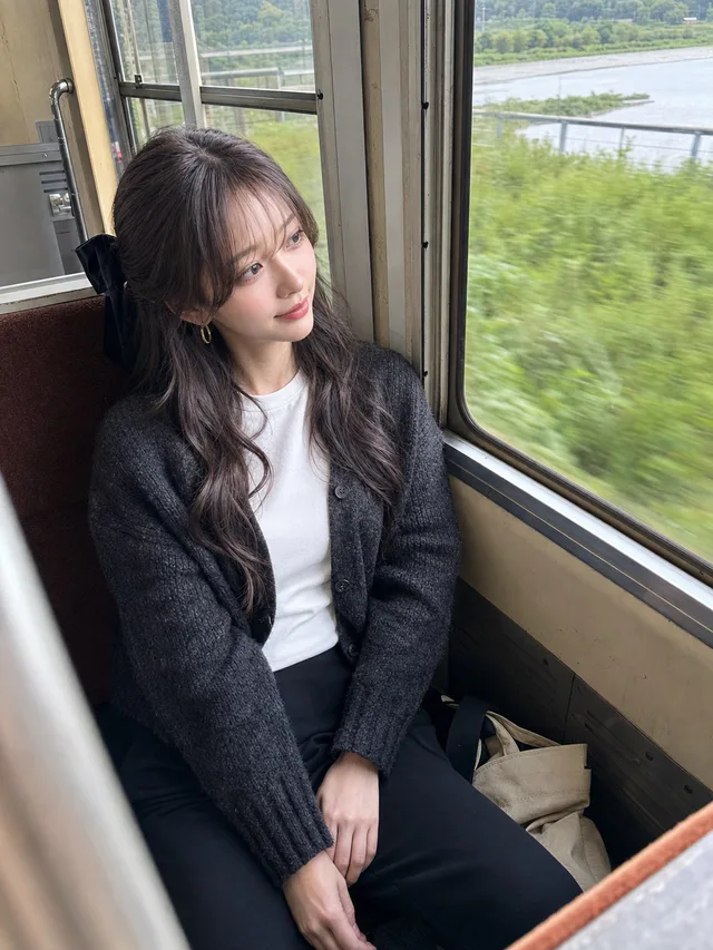 古いローカル線の窓際でチャコールのカーディガンと白いTシャツを着て、流れる車窓を眺める神崎セナ